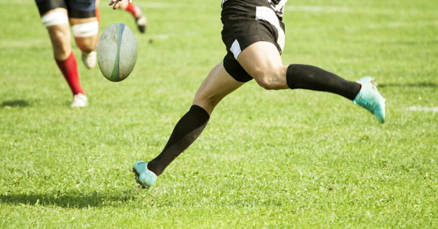 rugby player kicking the ball in open play